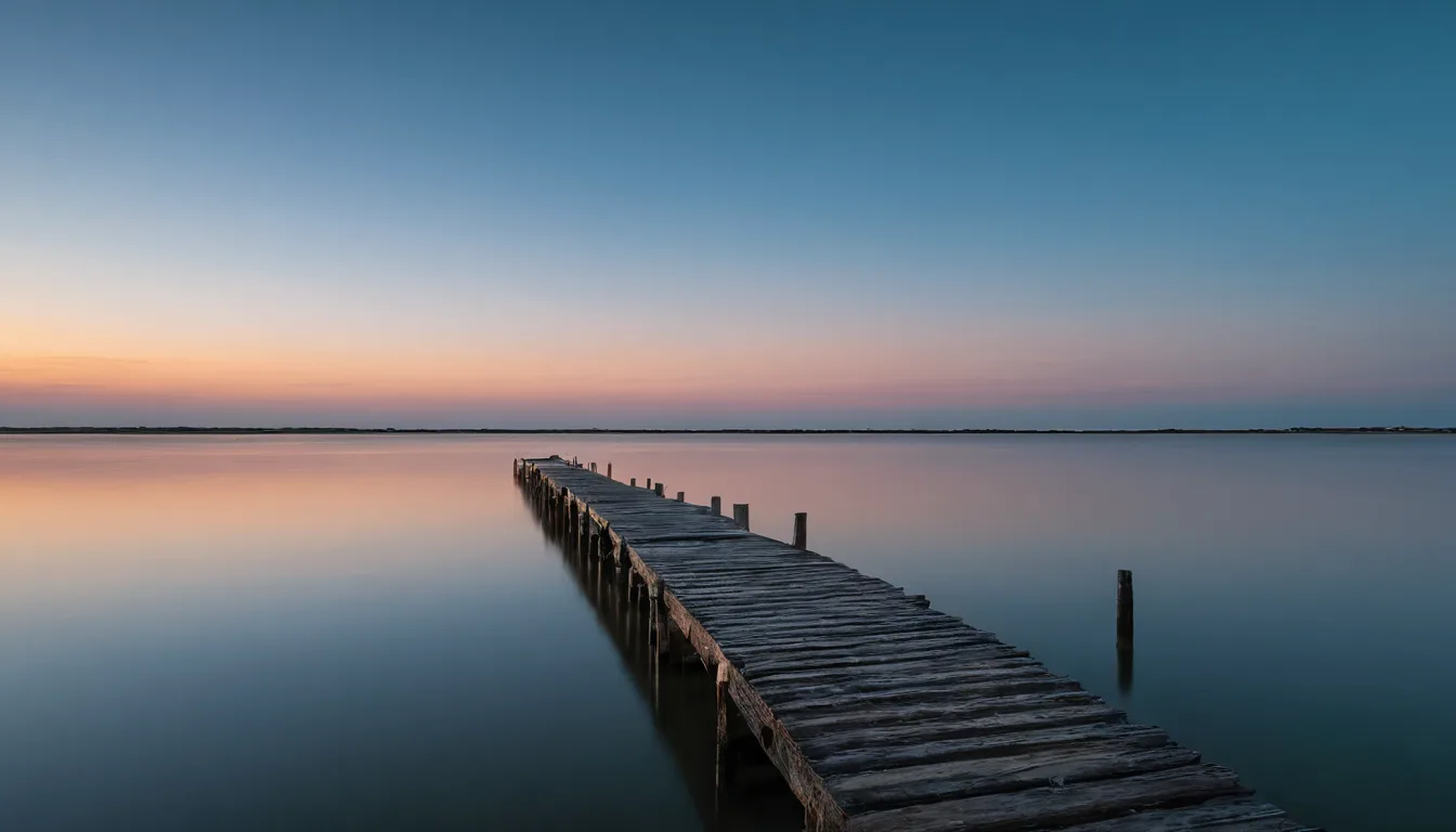 A calm Texas lake at dusk with a wooden pier